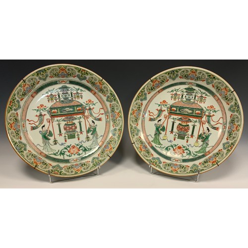 425 - A pair of Chinese famille vert dished circular chargers, each decorated with a Temple and Alter, fla... 