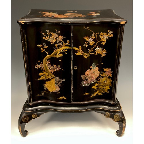 438 - A Japanese black lacquered serpentine two door cabinet, decorated with insects and birds amongst bra... 