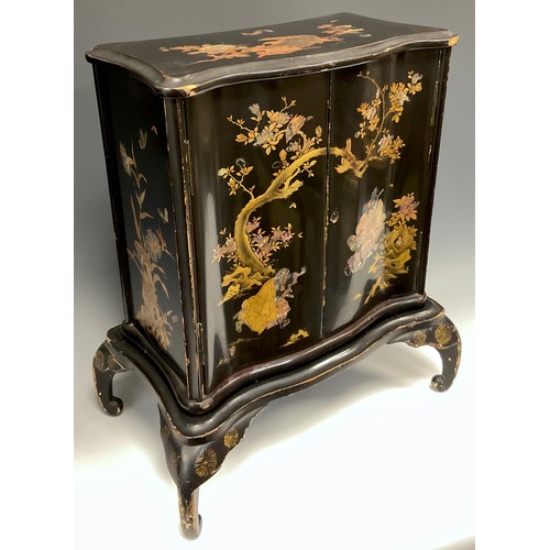 438 - A Japanese black lacquered serpentine two door cabinet, decorated with insects and birds amongst bra... 