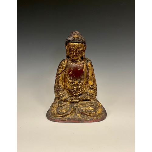 437 - A Chinese or Tibetan gilt and red patinated cast metal figure, Buddha seated crossed legs at prayer,... 