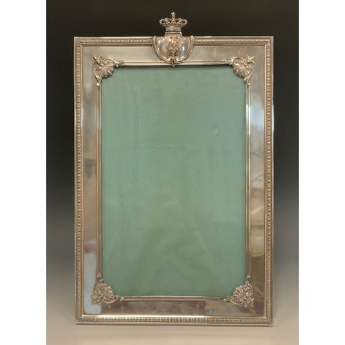 130 - A large early 20th century electroplated easel photograph frame, crested by a cartouche surmounted b... 