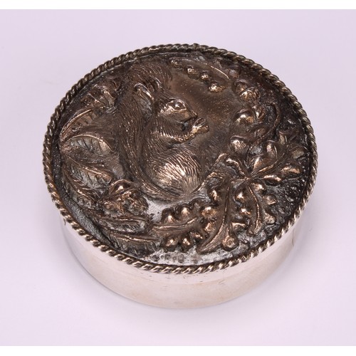 101 - An Elizabeth II silver circular trinket box, the push-fitting cover in relief with a squirrel, enclo... 