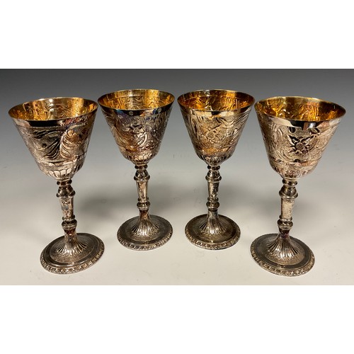 70 - A set of four Elizabeth II silver wine goblets, each with gilt bowls, embossed floral and foliate co... 