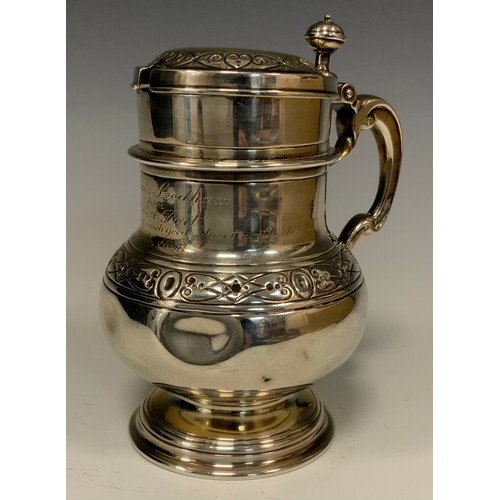 86 - A Victorian silver lidded tankard, waisted body with Celtic band of scrolling motif and rings, shape... 