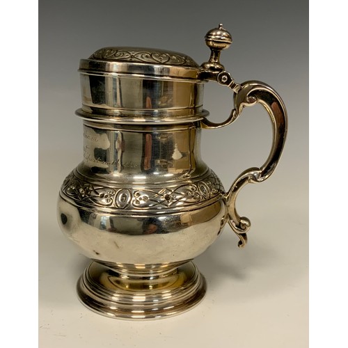 86 - A Victorian silver lidded tankard, waisted body with Celtic band of scrolling motif and rings, shape... 