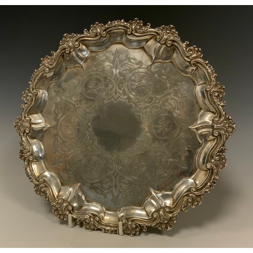 89 - A Victorian silver salver, chased floral centre within shell and scroll border, tripod scrolling fee... 