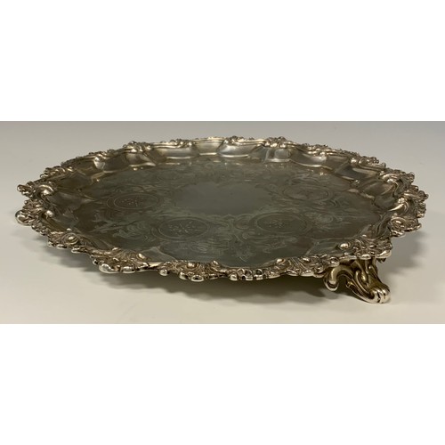 89 - A Victorian silver salver, chased floral centre within shell and scroll border, tripod scrolling fee... 