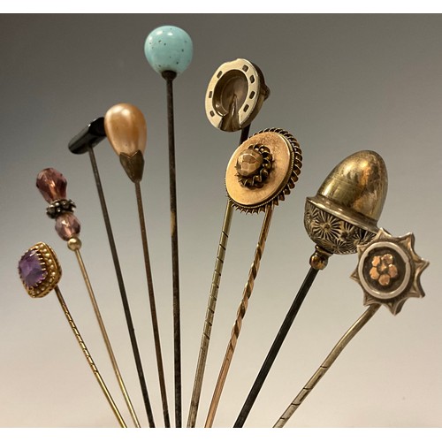 176 - A collection of nine 19th century and later scarf pins, including 9ct gold mounted pale pinky purple... 