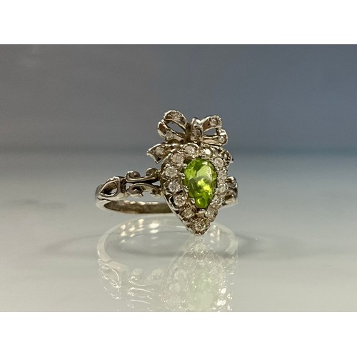 240 - A Regency style diamond and peridot ribbon heart dress ring, central pear cut peridot approx 0.96ct,... 