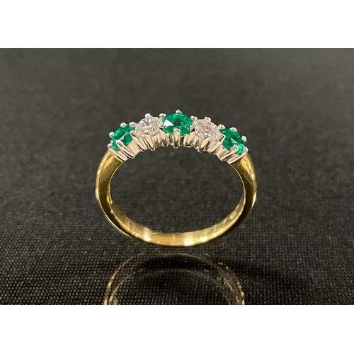 291 - An emerald and diamond ring, alternate set with three vibrant green emeralds and two round brilliant... 