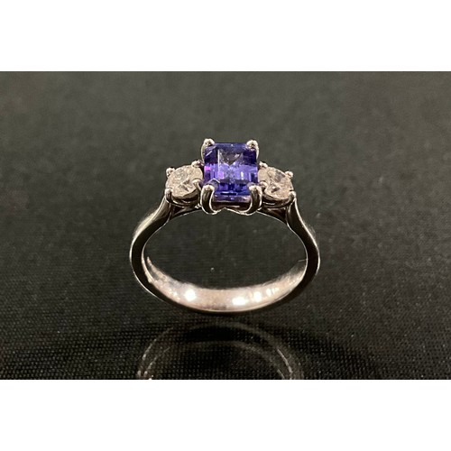 195 - A diamond and tanzanite ring, central rectangular emerald cut tanzanite, 1.39ct, flanked by a round ... 