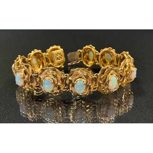 296 - An opal eleven section handcrafted bracelet, each oval floral panel set with a single cabochon opal,... 