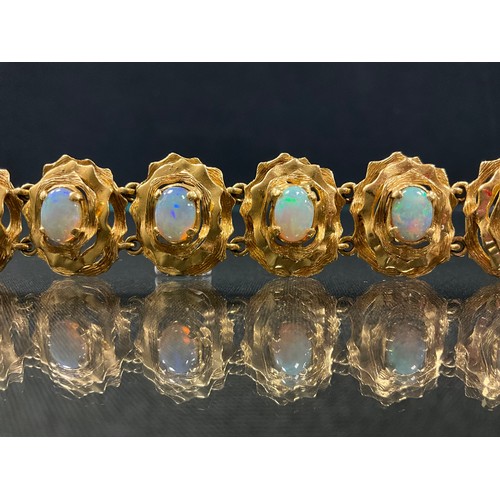 296 - An opal eleven section handcrafted bracelet, each oval floral panel set with a single cabochon opal,... 