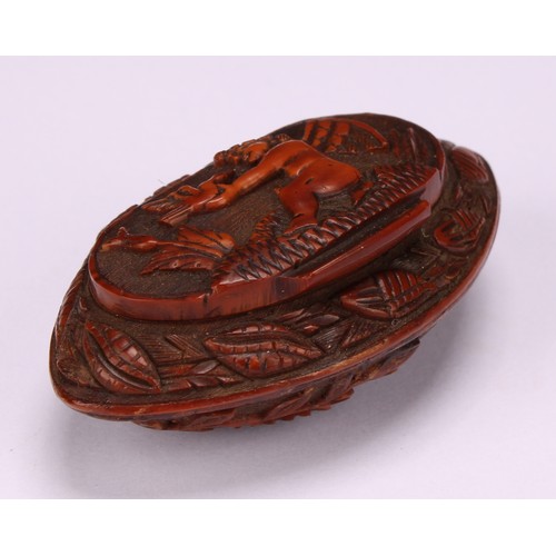 631 - Snuff - a 19th century navette shaped coquilla nut snuff box, carved with musical trophies and cupid... 