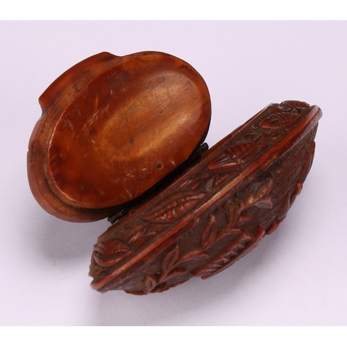 631 - Snuff - a 19th century navette shaped coquilla nut snuff box, carved with musical trophies and cupid... 