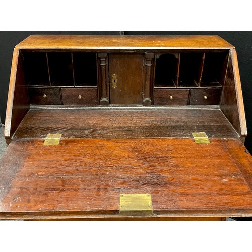 1123 - A George III oak bureau, of small proportions, fall door to top enclosing a fitted interior, with ce... 