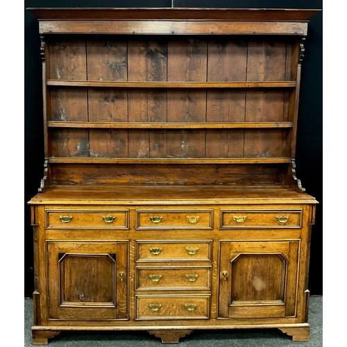 1215 - A George III revival oak dresser, the out-swept cornice above three tiers of plate-rack shelving, wi... 