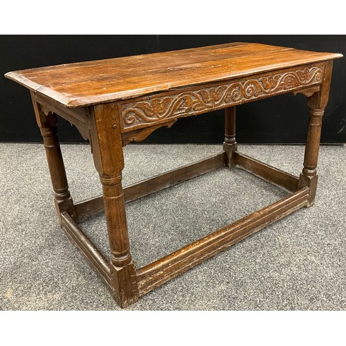 876 - An 18th century oak side table, oversailing planked top above a deep frieze carved meandering flower... 