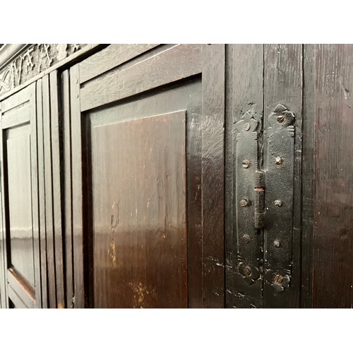 865 - A Charles II oak panelled hall cupboard, out-swept cornice above a carved frieze and a pair of panel... 