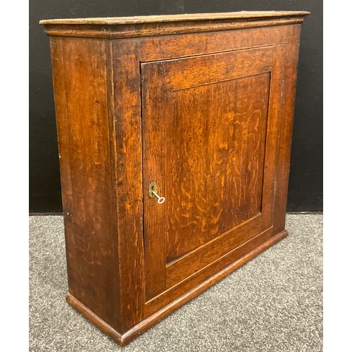 1066 - A George III oak wall-mounted cupboard, the single large oak-panelled door enclosed two tiers of she... 