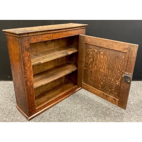 1066 - A George III oak wall-mounted cupboard, the single large oak-panelled door enclosed two tiers of she... 