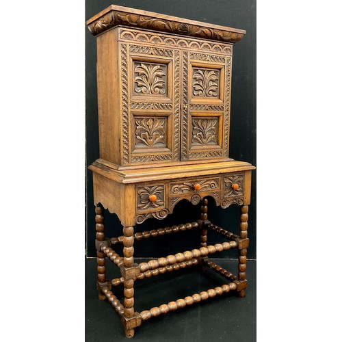 1237 - A Jacobean Revival oak hall cupboard, the cornice, doors, and drawer fronts carved in deep relief wi... 