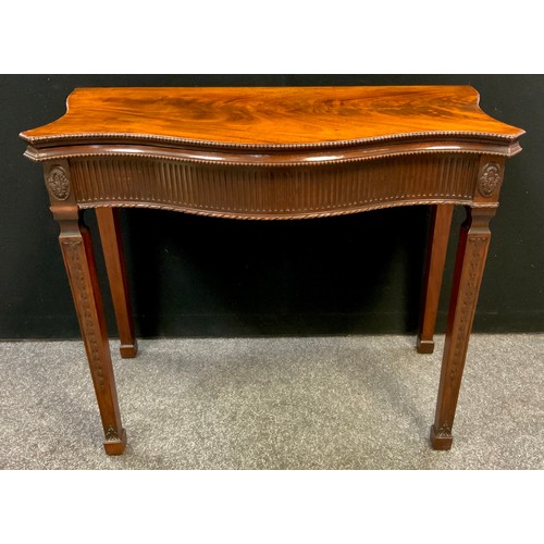 909 - A Hepplewhite style mahogany games table, the flame mahogany serpentine shaped top, above a fluted f... 