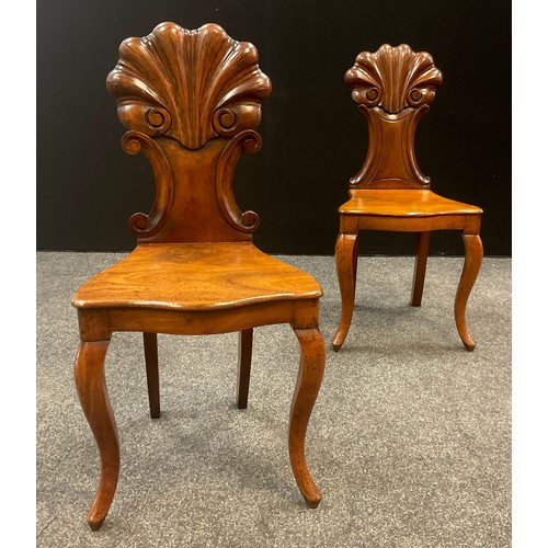 911 - A similar pair of 19th century walnut hall chairs, the carved scallop backs with c-scroll sides, ove... 