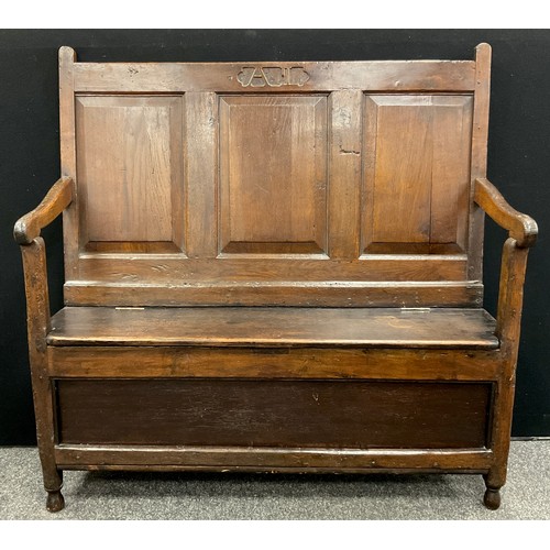 874 - An 18th century oak box settle, the tall back with three rectangular raised and fielded panels, carv... 