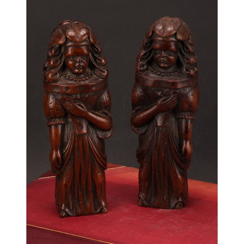 1242 - A pair of Continental walnut appliques, each carved as a lady of the court holding a flower to her b... 