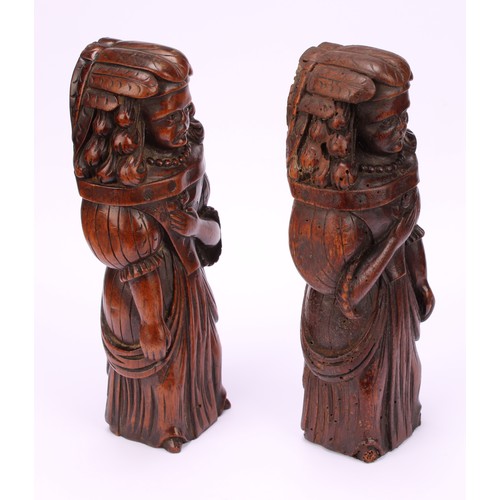 1242 - A pair of Continental walnut appliques, each carved as a lady of the court holding a flower to her b... 