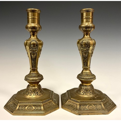 1226 - A pair of 18th century French brass table candlesticks, of seamed construction, cast with portrait r... 