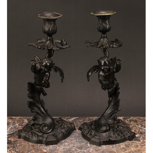 1230 - A pair of 19th century dark patinated bronze mantle sticks, cast with cherubs flying amongst stylise... 