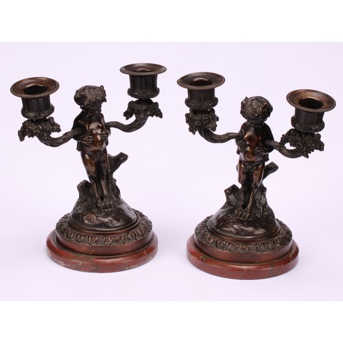 1231 - A pair of 19th century French figural two-light mantle candelabrum, cast as fauns standing holding f... 