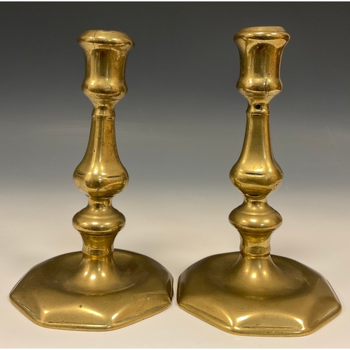 1244 - A pair of George I/II brass candlesticks, of seamed construction, square knopped pillars, octagonal ... 