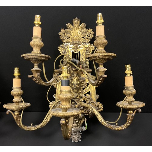 1023 - A pair of Baroque Renaissance style gilt metal wall lights, cast floral wall mounts with mask heads,... 