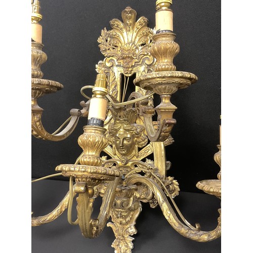 1023 - A pair of Baroque Renaissance style gilt metal wall lights, cast floral wall mounts with mask heads,... 