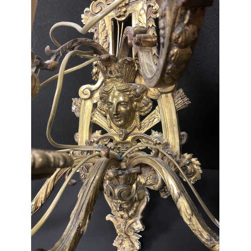 1023 - A pair of Baroque Renaissance style gilt metal wall lights, cast floral wall mounts with mask heads,... 