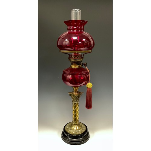 1027 - A Victorian style ruby glass and brass oil lamp, ruby reservoir and shade, spiralled column, black f... 