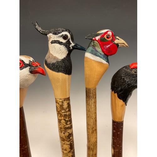 665 - A group of five hand-carved walking canes / walking sticks, the handles carved and painted as the he... 