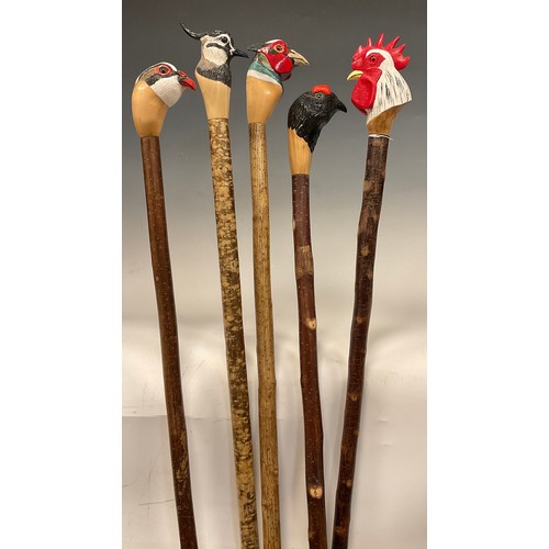 665 - A group of five hand-carved walking canes / walking sticks, the handles carved and painted as the he... 