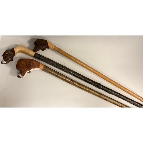 674 - A trio of hand-carved walking canes / walking sticks, each of the handles carved and painted as the ... 