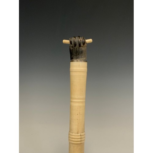 692 - An early 20th century turned and caved bone and ebony walking stick, clenched fist handle, tapering ... 