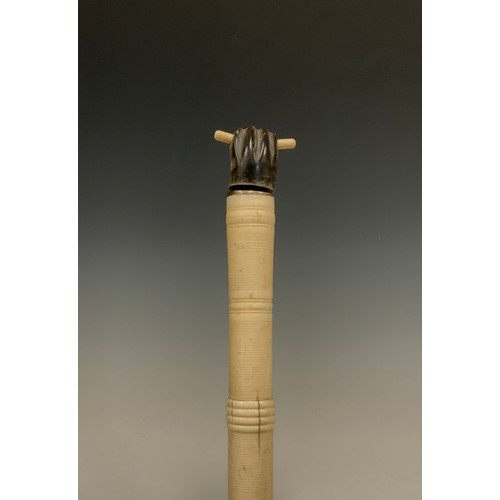 692 - An early 20th century turned and caved bone and ebony walking stick, clenched fist handle, tapering ... 