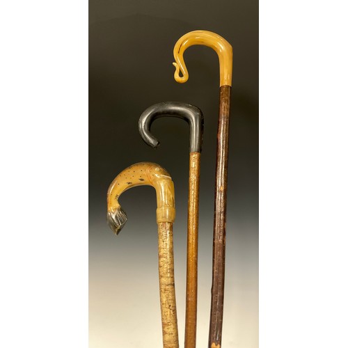 699 - A Shepherd’s crook, the cow horn handle carved as a leaping trout, 136cm high;  two other crooks, la... 