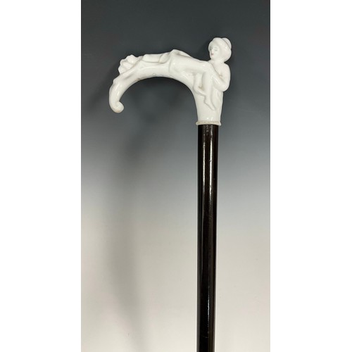 707 - A late 19th century walking cane, the white glazed porcelain handle / pommel, modelled as two scanti... 