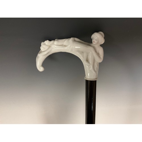 707 - A late 19th century walking cane, the white glazed porcelain handle / pommel, modelled as two scanti... 