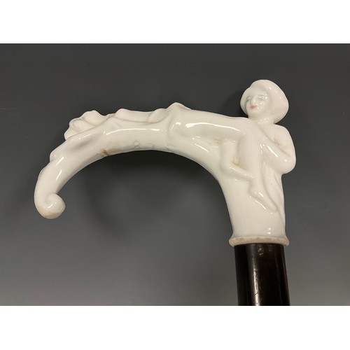 707 - A late 19th century walking cane, the white glazed porcelain handle / pommel, modelled as two scanti... 