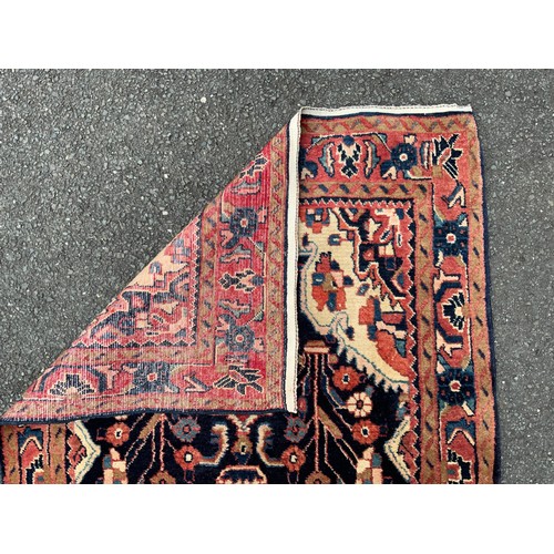 1085 - A large Persian Navahand runner carpet, hand-knotted with a central field of stylised flowers on a d... 