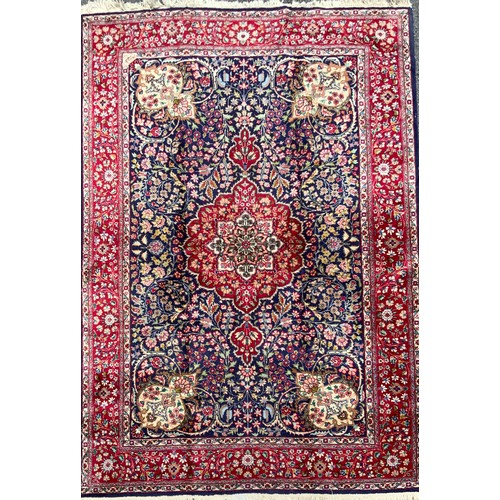 1283 - A Persian Tabriz carpet, all over floral garden design in red, blue, crean, green and pink on a red ... 